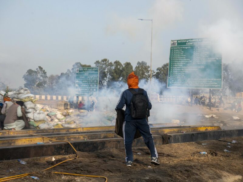 Photo of farmers protesting in India and running away from tear gas