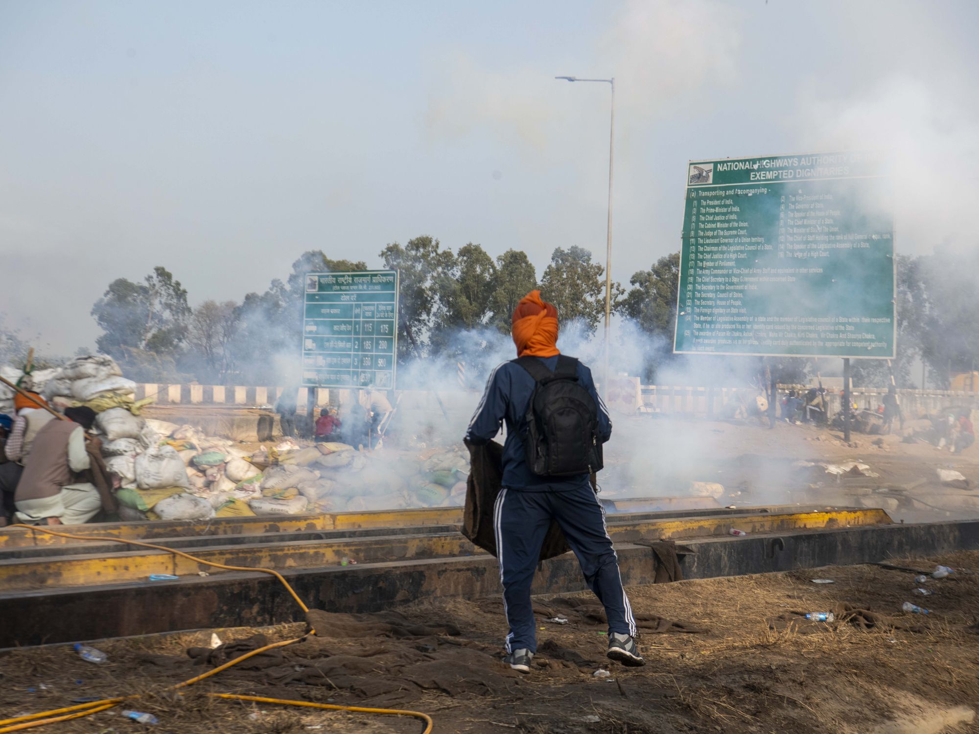 Photo of farmers protesting in India and running away from tear gas