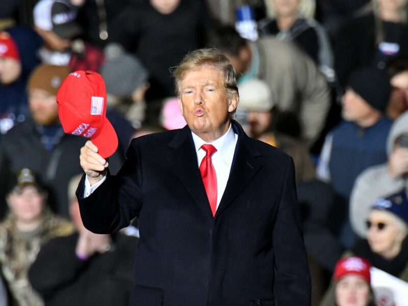 Photo of Former President Donald Trump tipping his red hat in front of an audience