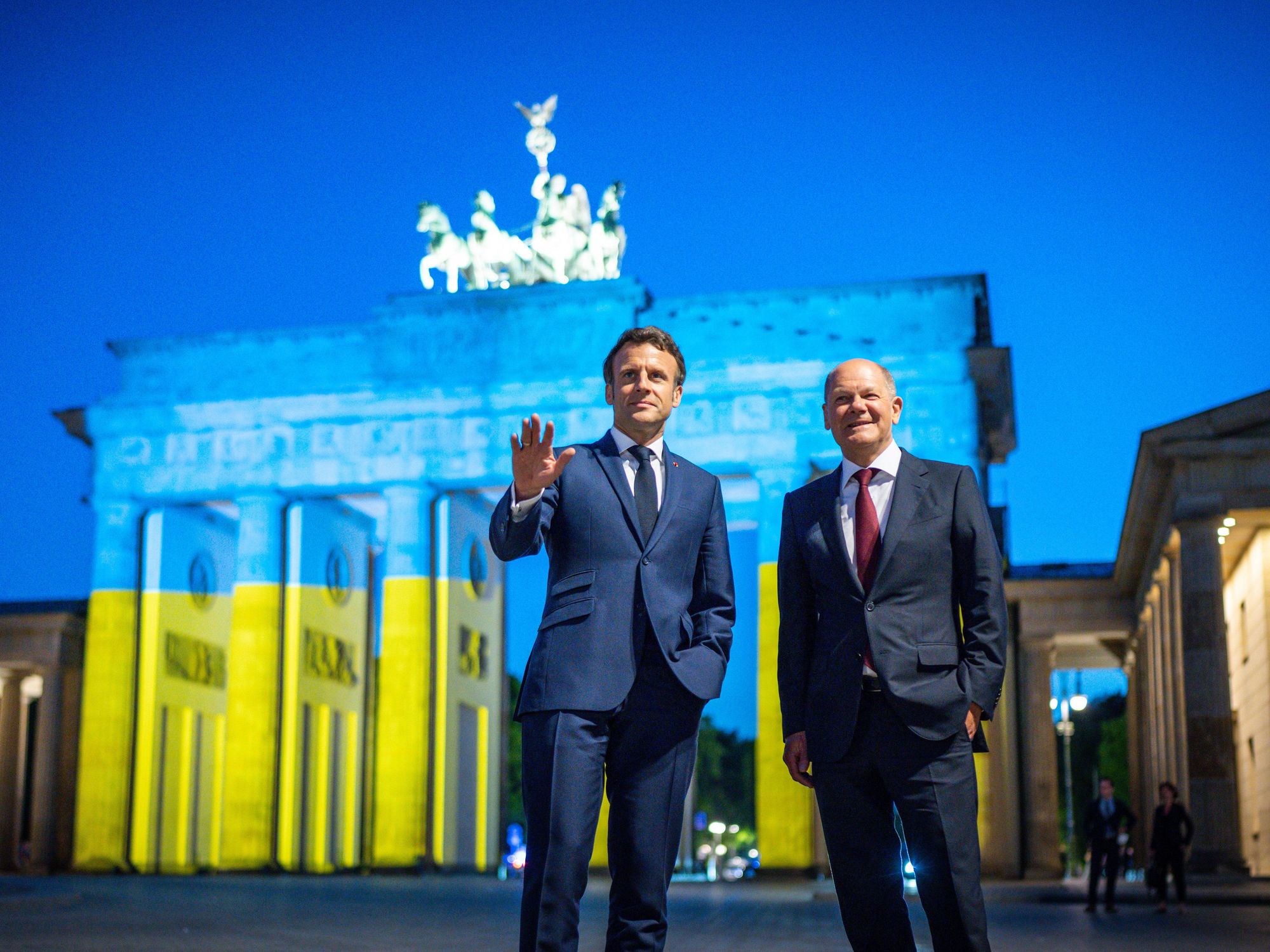 Photo of German Chancellor Olaf Scholz and French President Emmanuel Macron stand in front of the Brandenburg Gate in Berlin on May 9