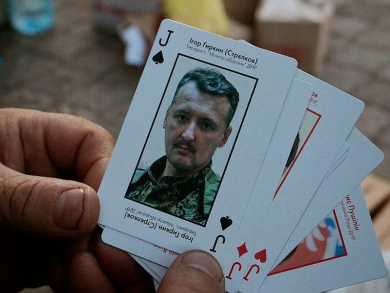 Photo of hands holding cards including one featuring Igor Girkin