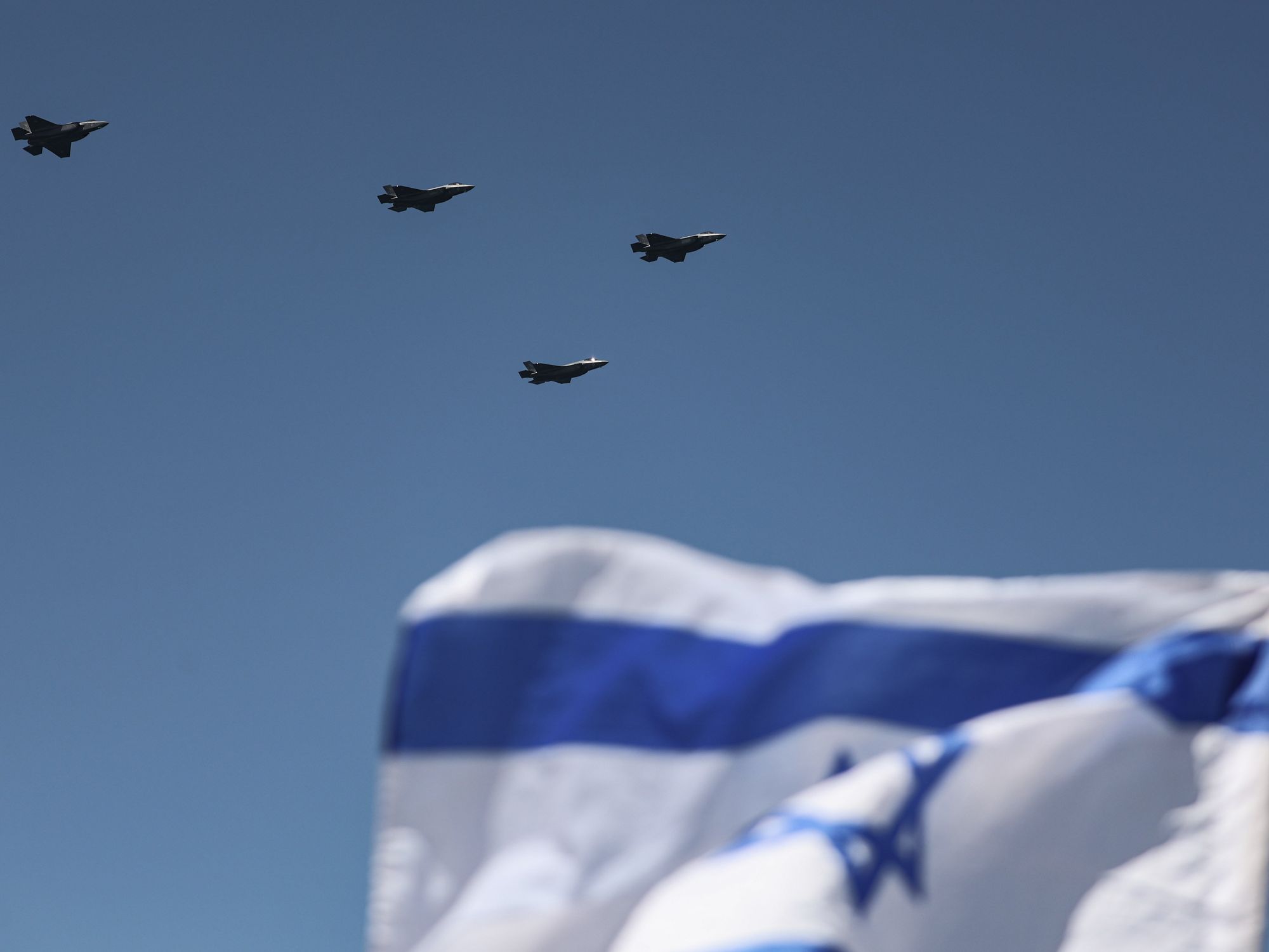 Photo of Israeli fighter jets flying above an Israeli flag in the foreground