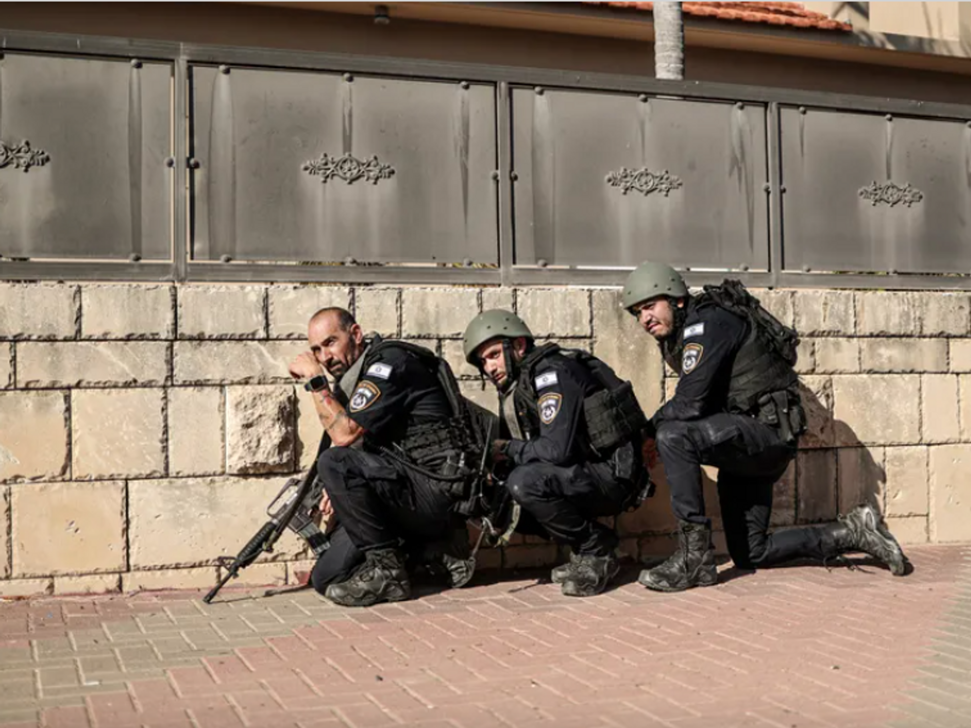 Photo of Israeli police officers taking cover behind a wall during a rocket attack from Gaza