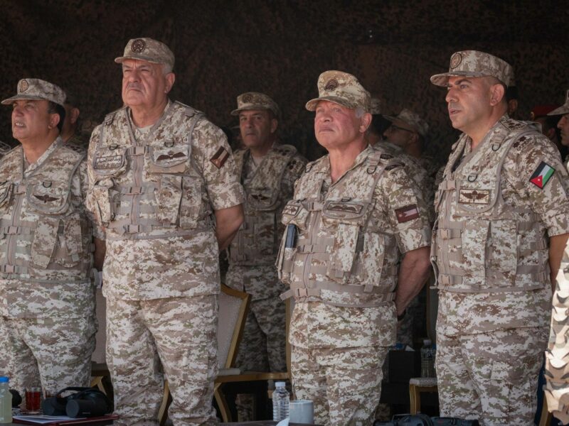 Photo of Jordan's King Abdullah II in military uniform surveying military exercises.