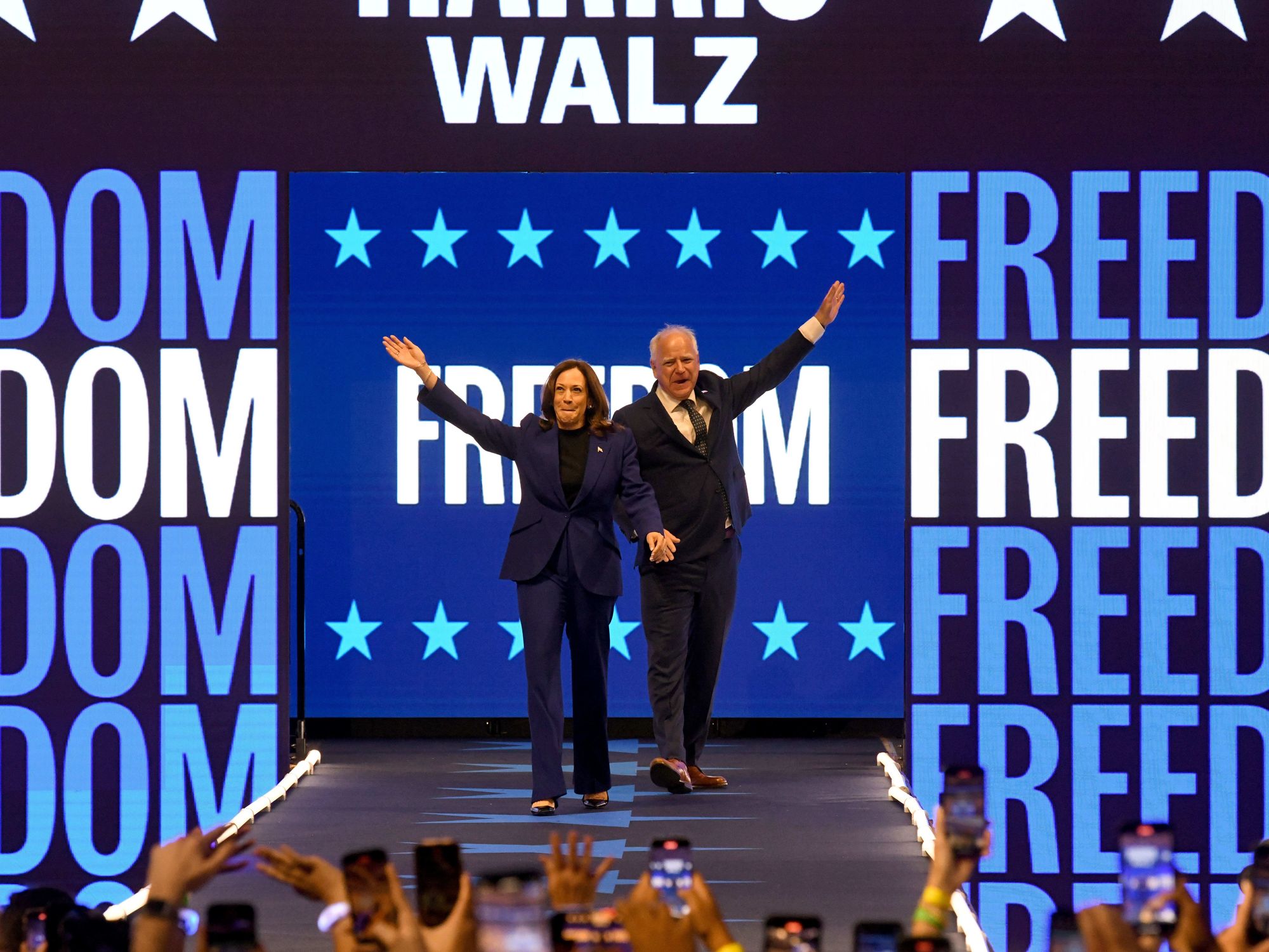 Photo of Kamala Harris and Tim Walz walking onstage at a campaign rally at Fiserv Forum in Milwaukee, Wisconsin on August 20.