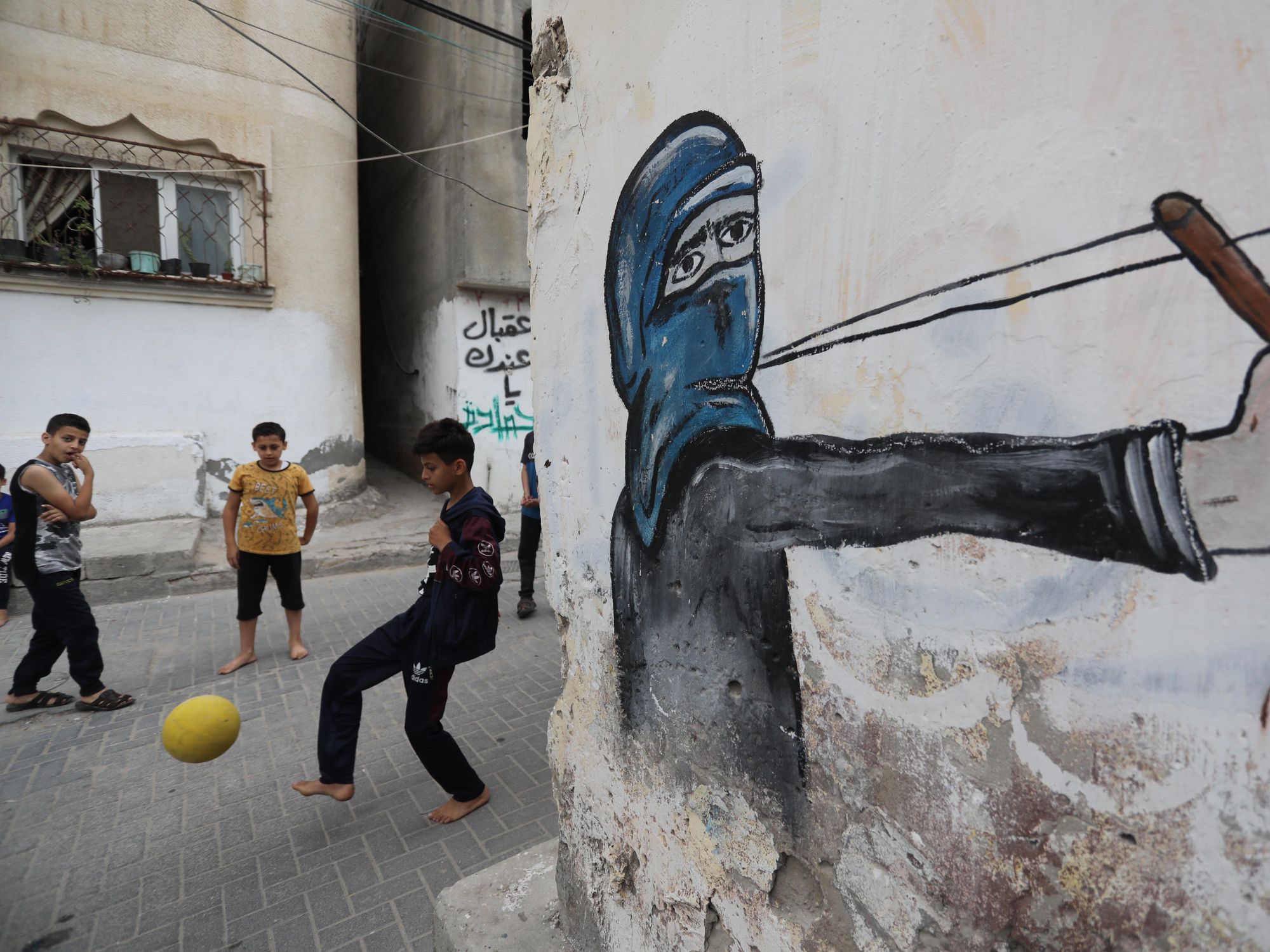 photo of kids playing soccer with a mural of someone shooting a slingshot