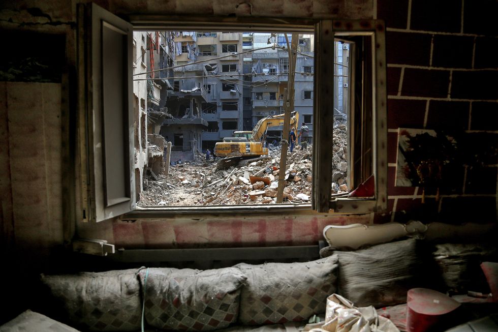 photo of Lebanese civil workers seen from window of devastated apartment as they still search between rubble of buildings destroyed by Israeli air raids in central Beirut as they salvage belongings from their devastated apartment prior the visit of Iranian Speaker of the Parliament Ghalibaf to inspect the place.