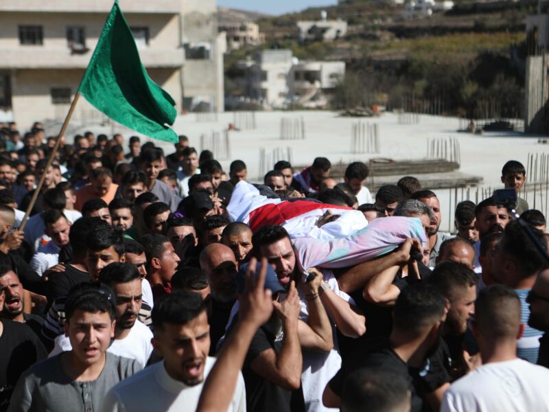 photo of lots of men carrying a corpse in a funeral