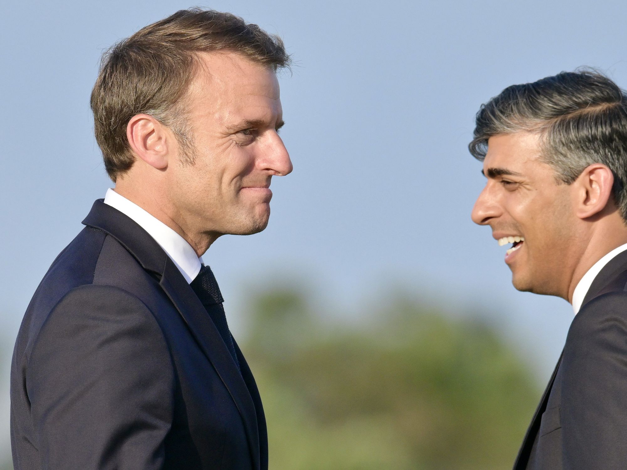 photo of Macron and Sunak facing each other and smiling.
