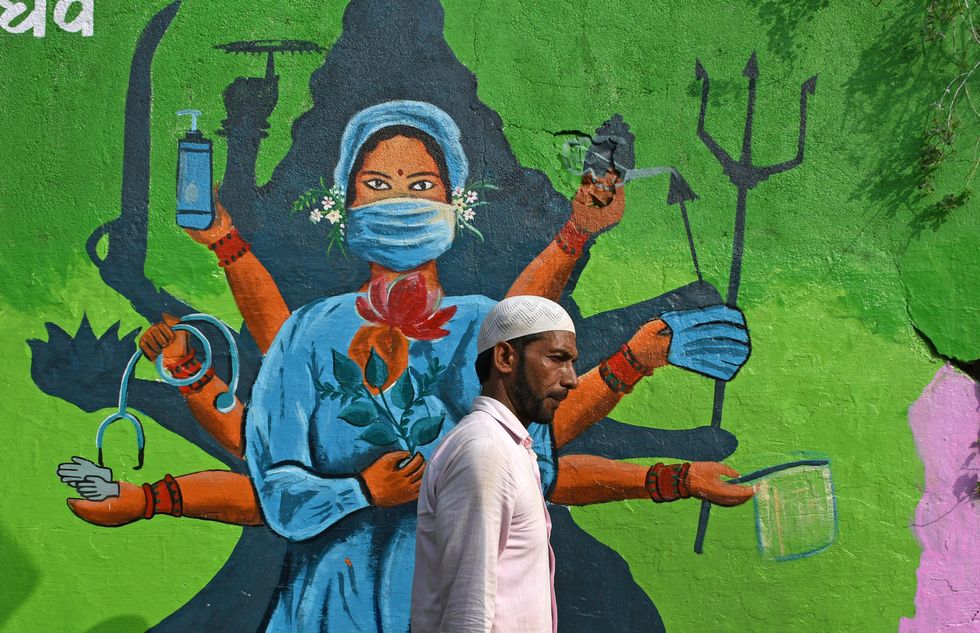photo of man walking past mural