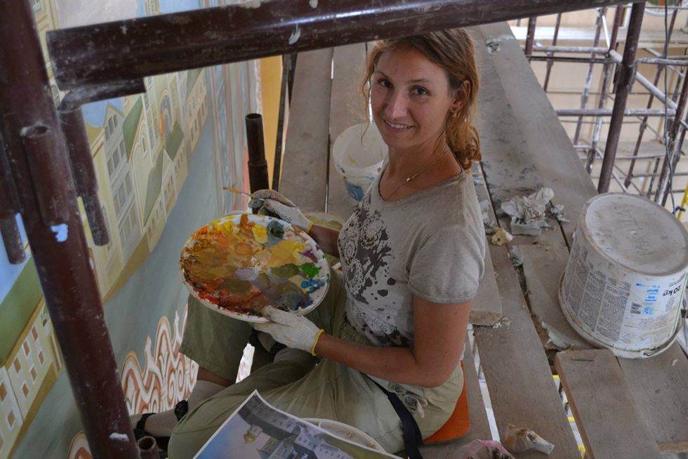Photo of Maria Makarevych painting the Cathedral of All Saints in 2013