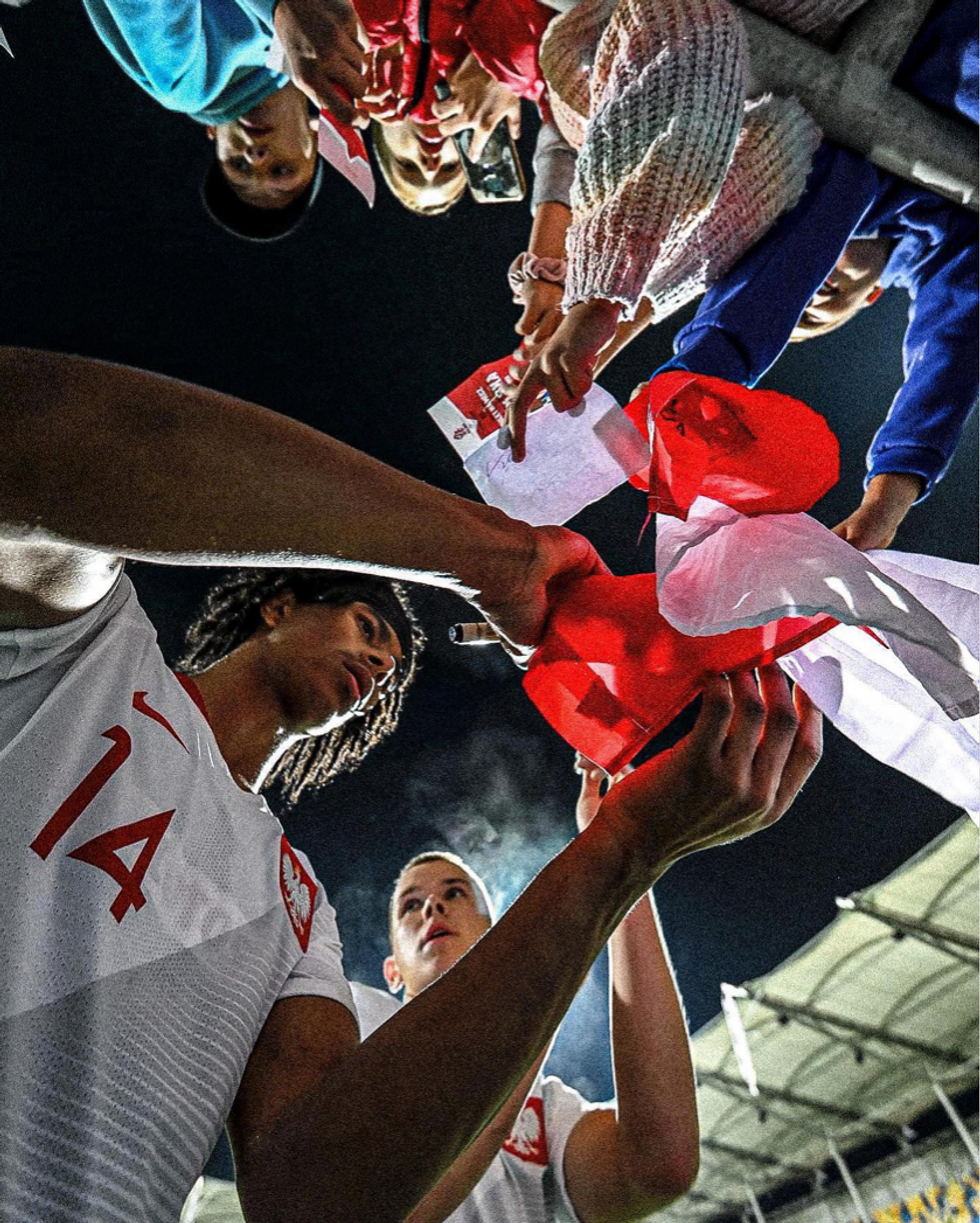 Photo of Maximillian Oyedele signing flags for fans.