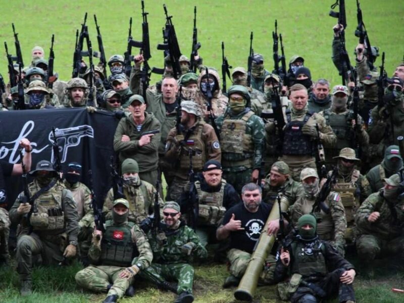 Photo of members of PMC Española, in gear and with weapons, posing for a group photo on a soccer pitch