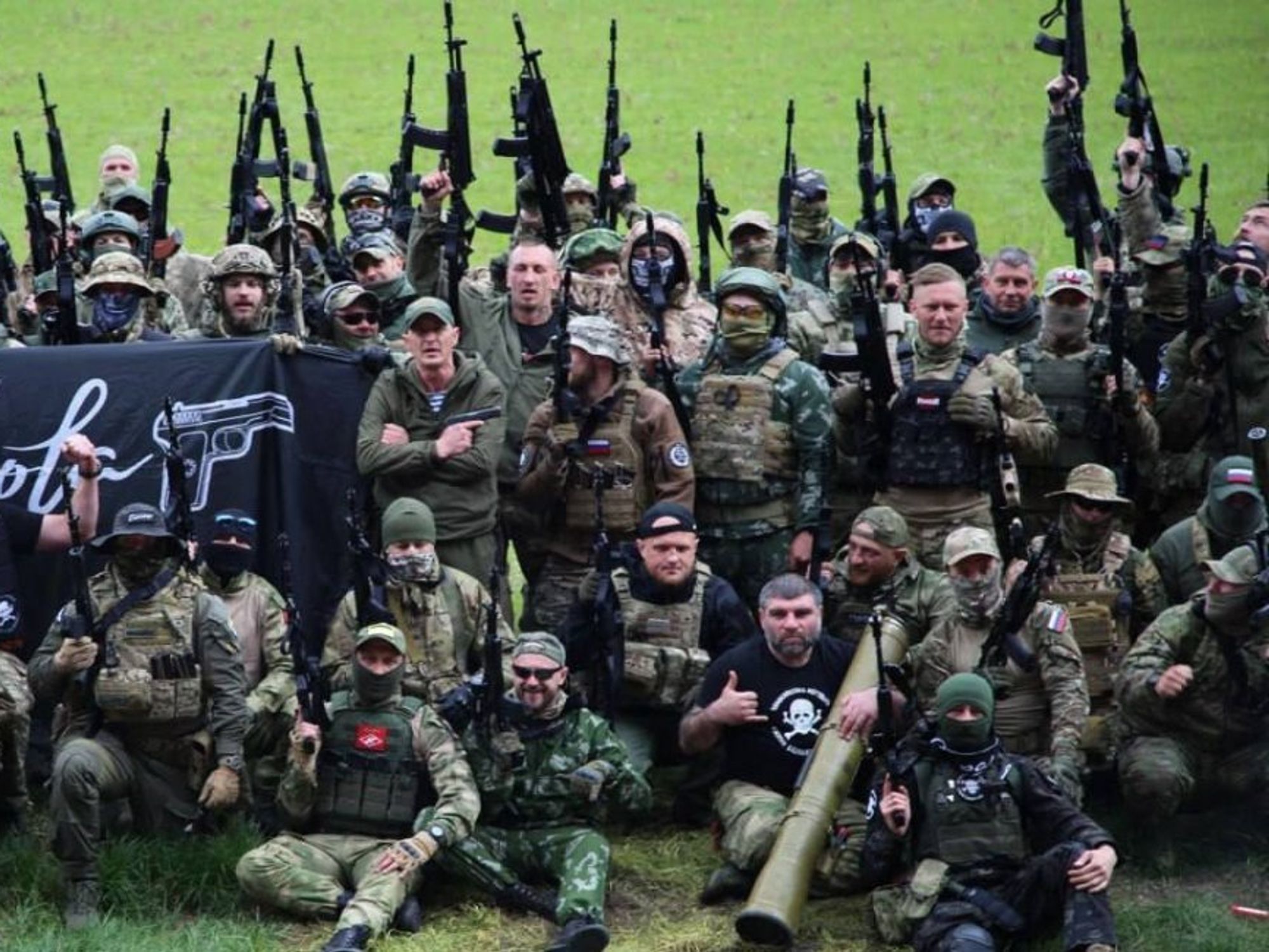 Photo of members of PMC Española, in gear and with weapons, posing for a group photo on a soccer pitch