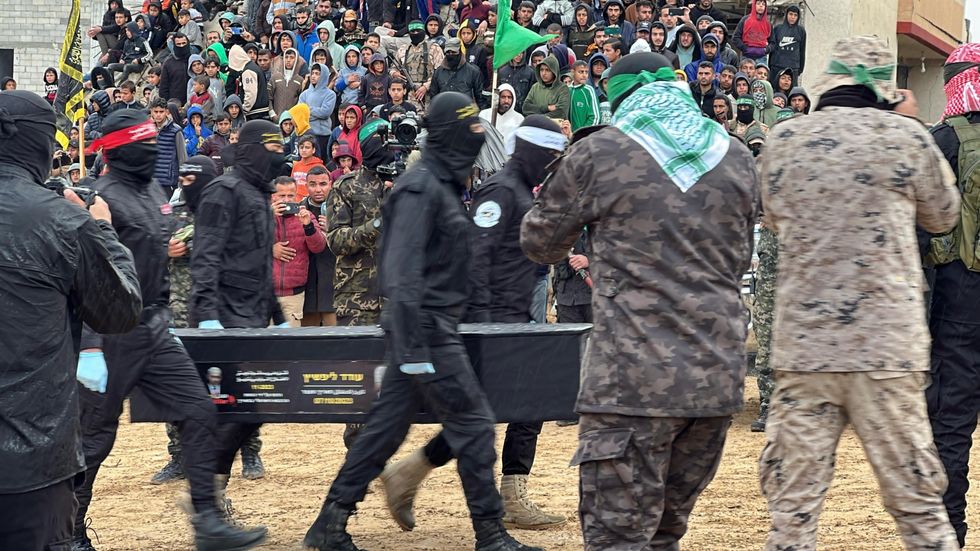 photo of men in black carrying a black coffin