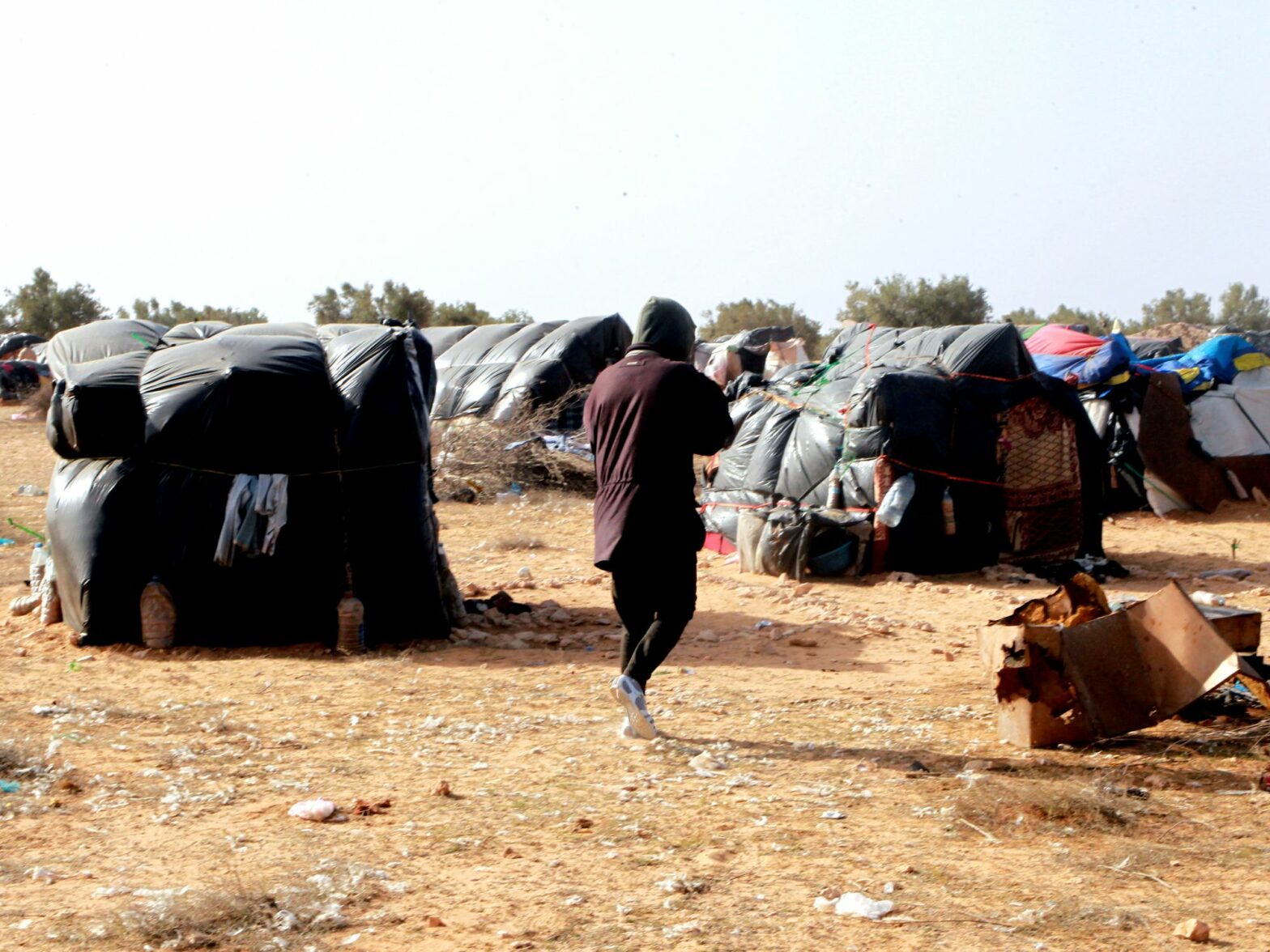 Photo of migrants from sub-Saharan Africa gather near tents in a camp in Jebeniana