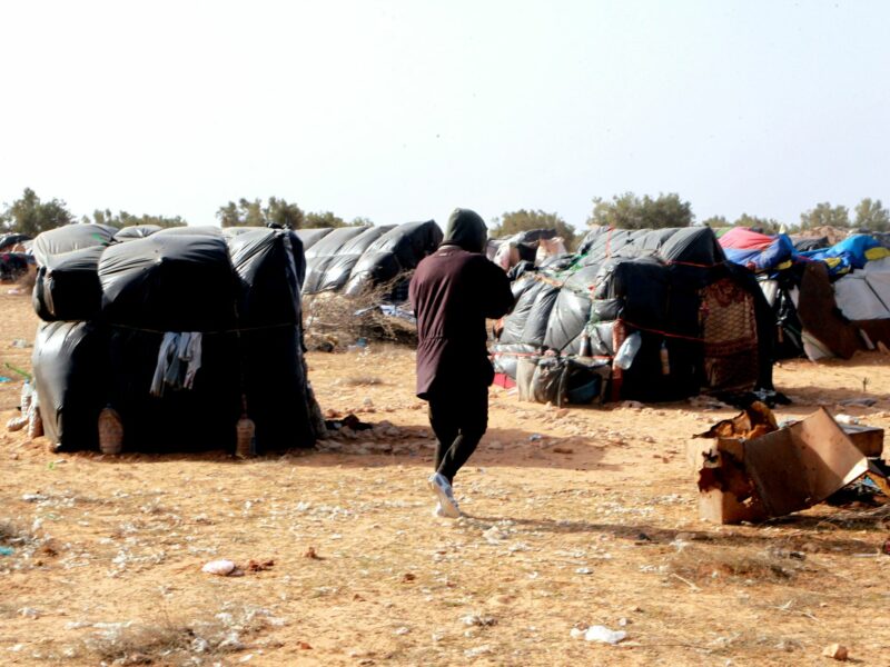 Photo of migrants from sub-Saharan Africa gather near tents in a camp in Jebeniana