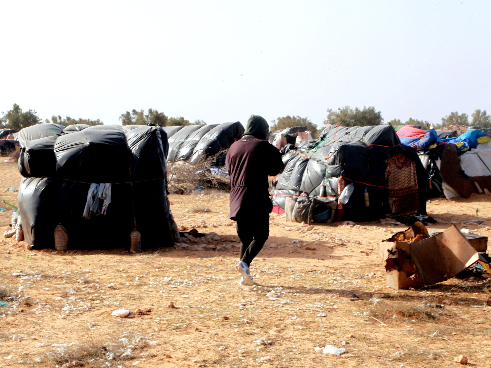 Photo of migrants from sub-Saharan Africa gather near tents in a camp in Jebeniana