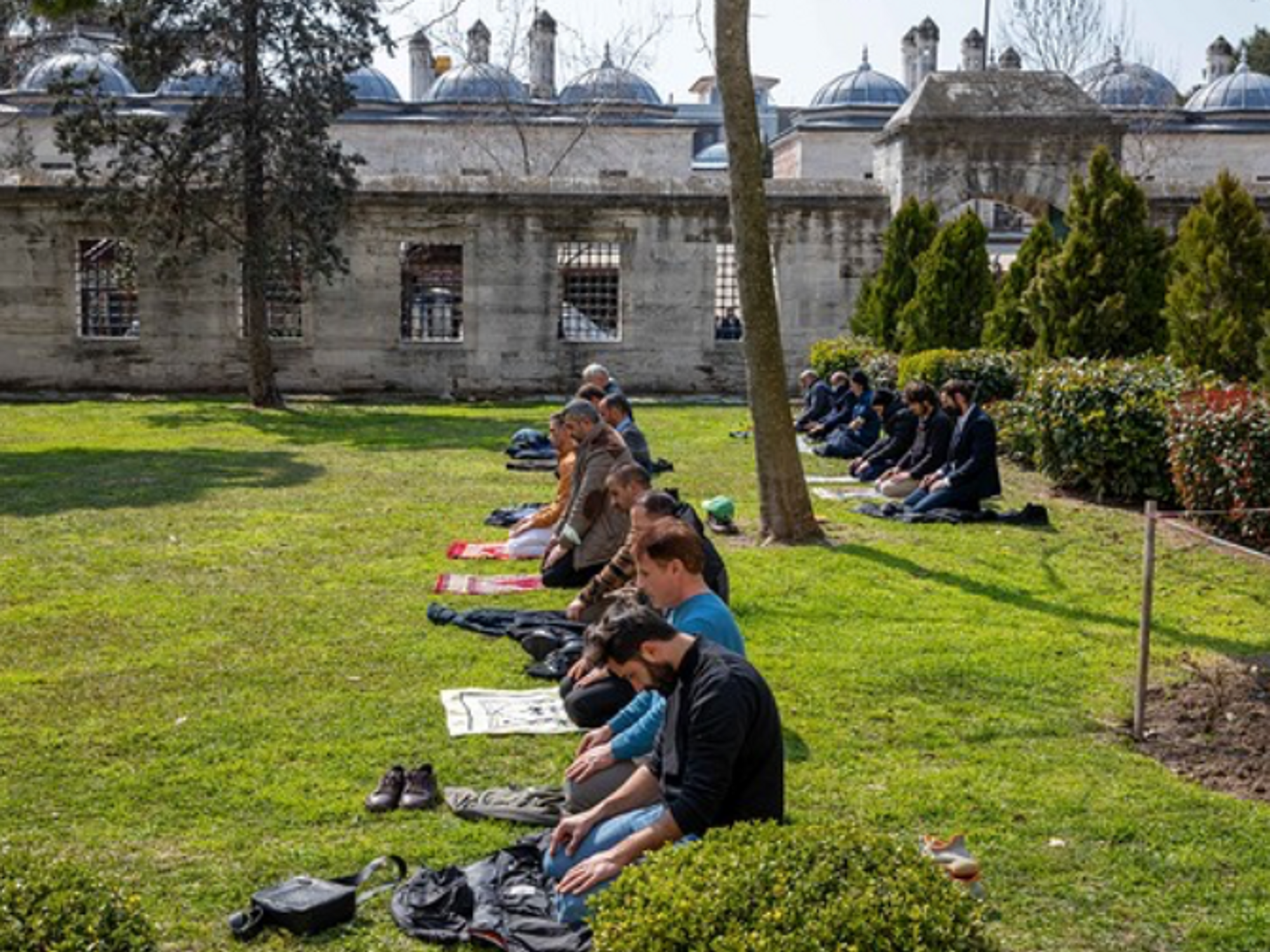 Photo of Muslims performing Friday prayer in the garden of Suleymaniye Mosque, Istanbul.