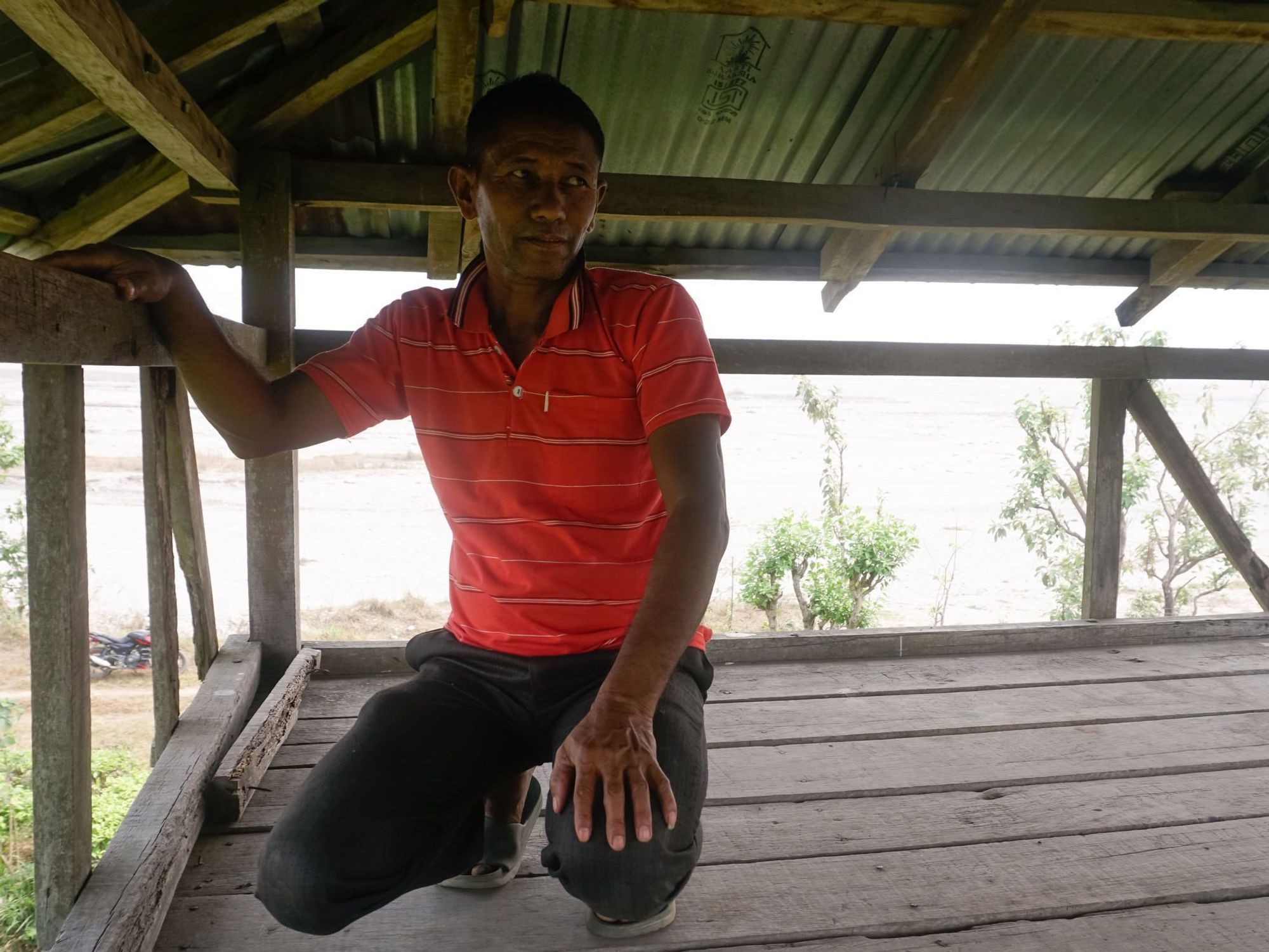 Photo of Nepalese farmer Motilal Bhujel crouching in an elephant watchtower.