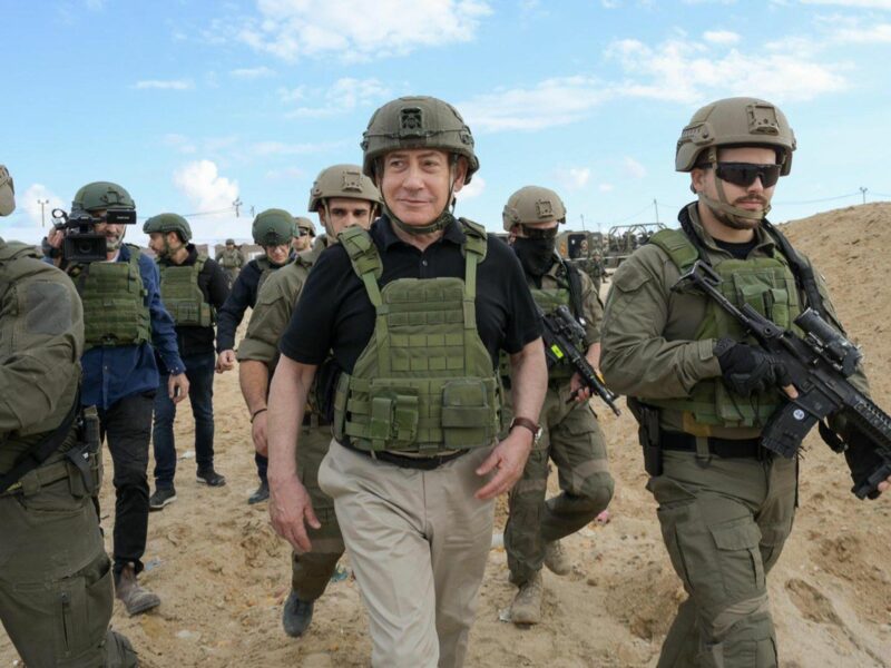 photo of Netanyahu in protective vest walking surrounded by soldiers