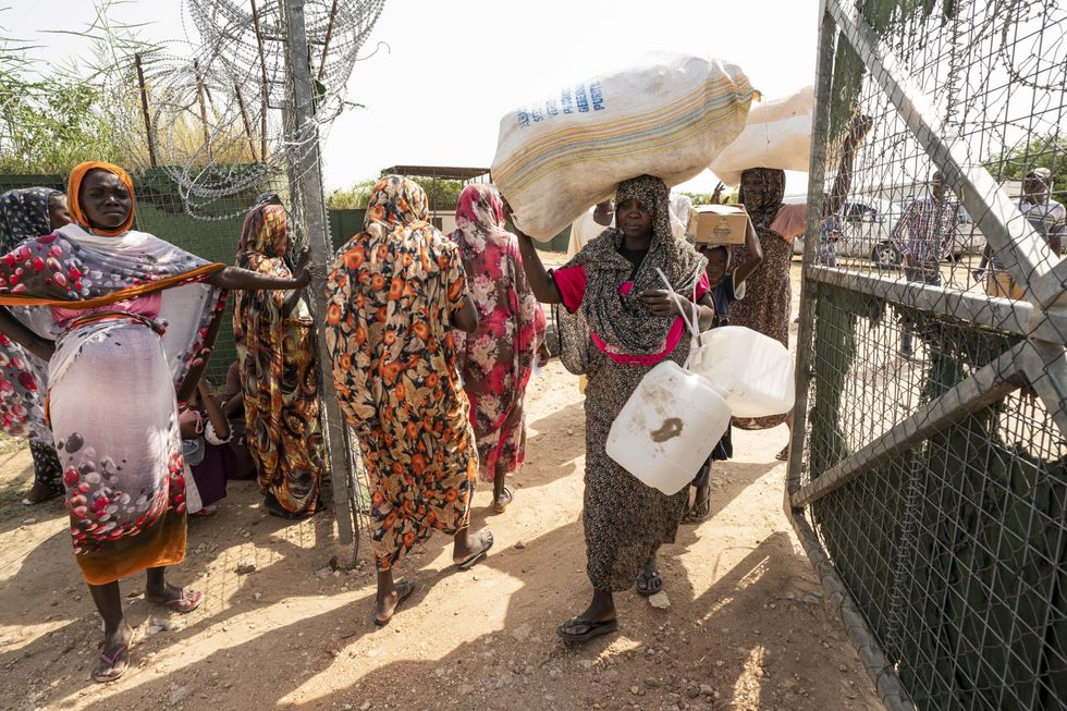 Photo of newly arrived internally displaced persons carrying non food items at a distribution coordinated by UNHCR and Norwegian Church Aid at the Otash IDP Camp near Nyala, South Darfur, Sudan.