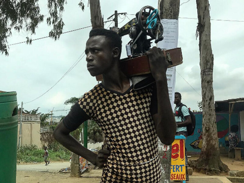 Photo of one of Ouagadougou's "rafistoleurs" carrying his sewing machine on his shoulder