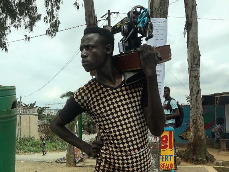 Photo of one of Ouagadougou's "rafistoleurs" carrying his sewing machine on his shoulder