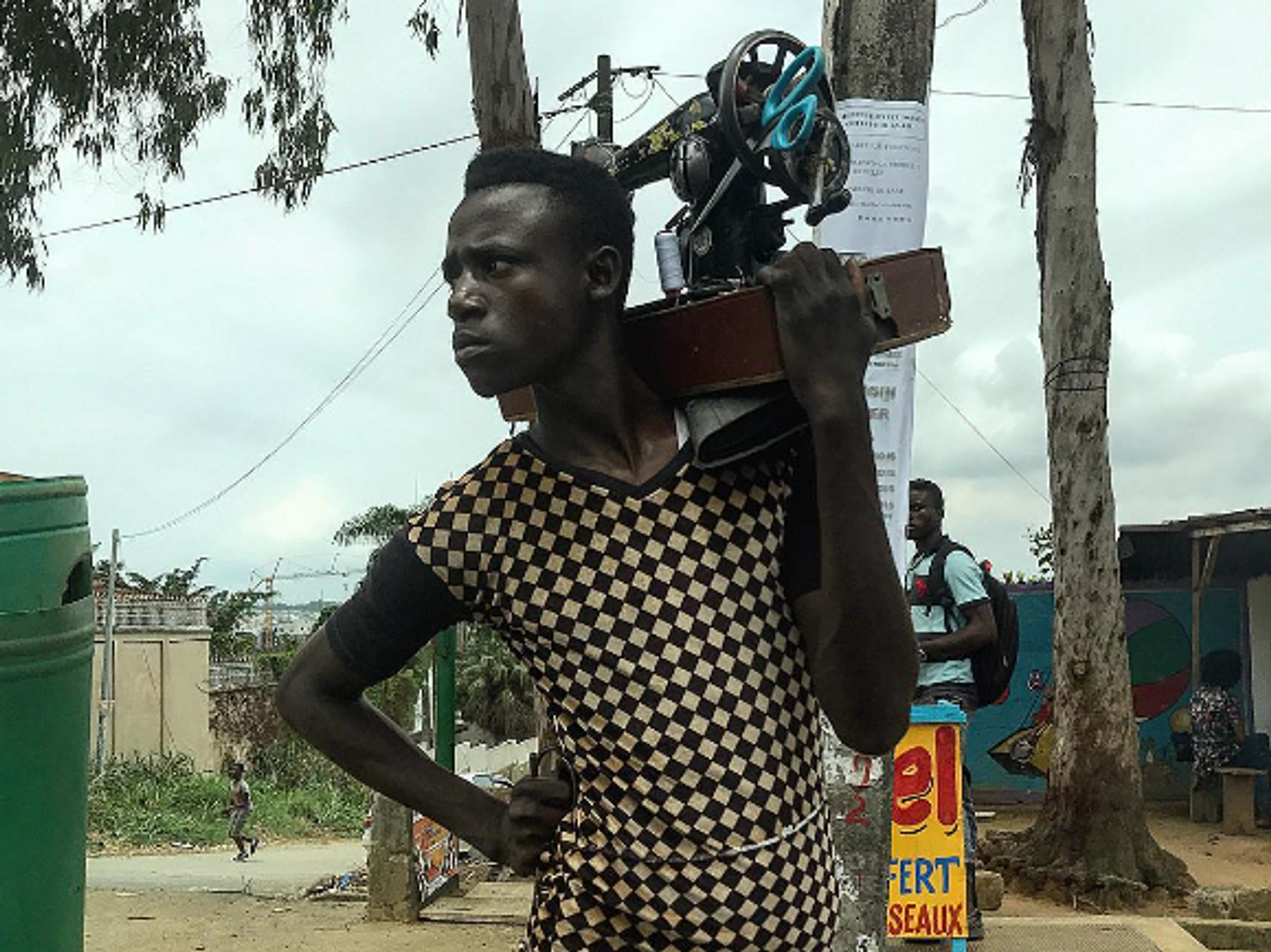 Photo of one of Ouagadougou's "rafistoleurs" carrying his sewing machine on his shoulder