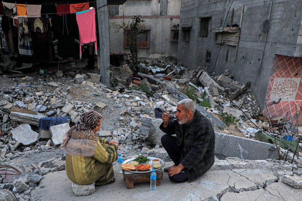 Photo of Palestinians eating on the rubble of their house in the central Gaza city of Deir el-Balah, on March 13.