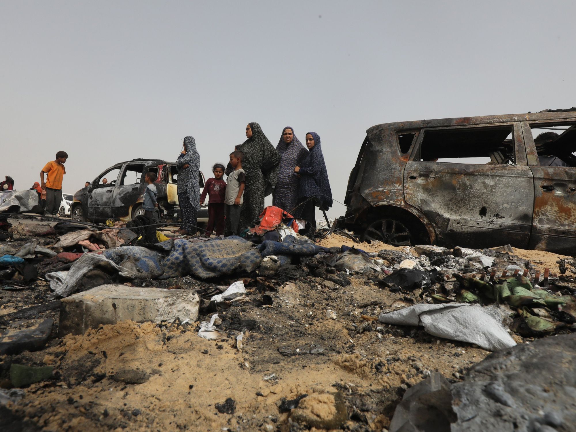 Photo of Palestinians looking at charred debris in Rafah, Gaza, after Israeli airstrikes on May 27