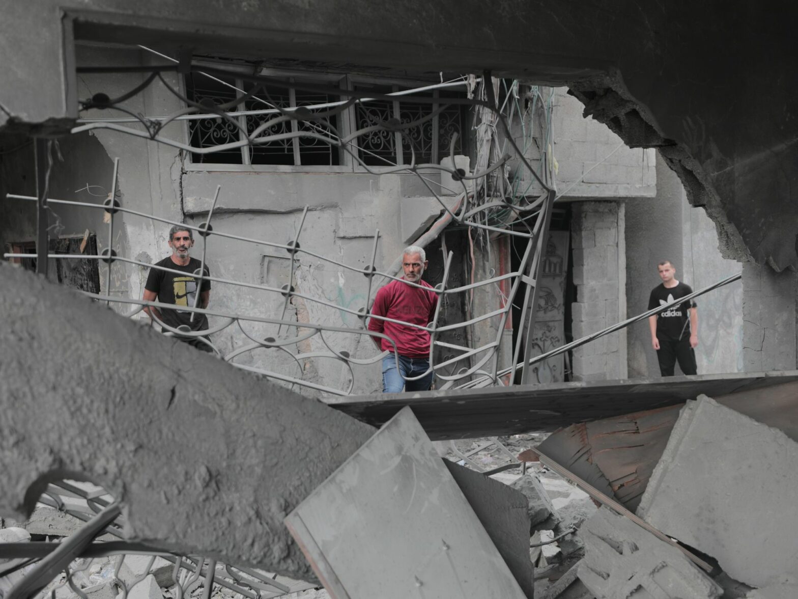 Photo of Palestinians standing among the rubble, inspecting the damage