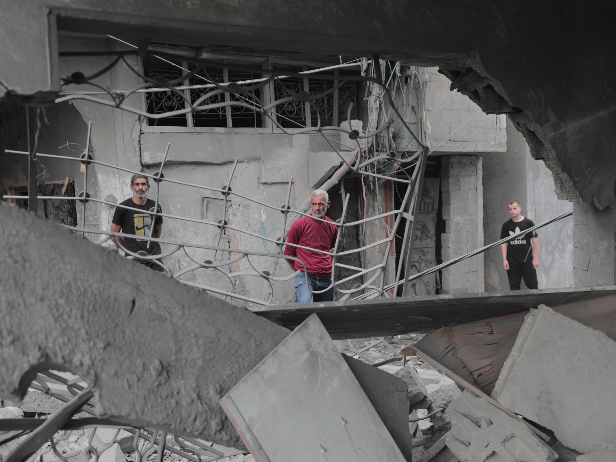 Photo of Palestinians standing among the rubble, inspecting the damage