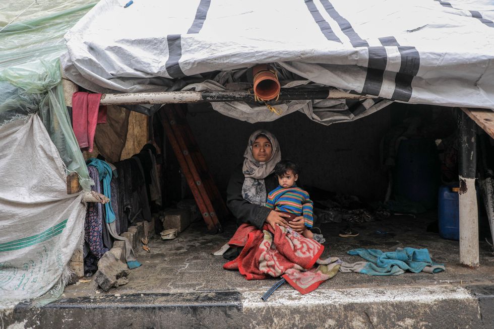 Photo of Palestinians taking shelter underneath a makeshift tent at a camp in Rafah in the southern part of Gaza