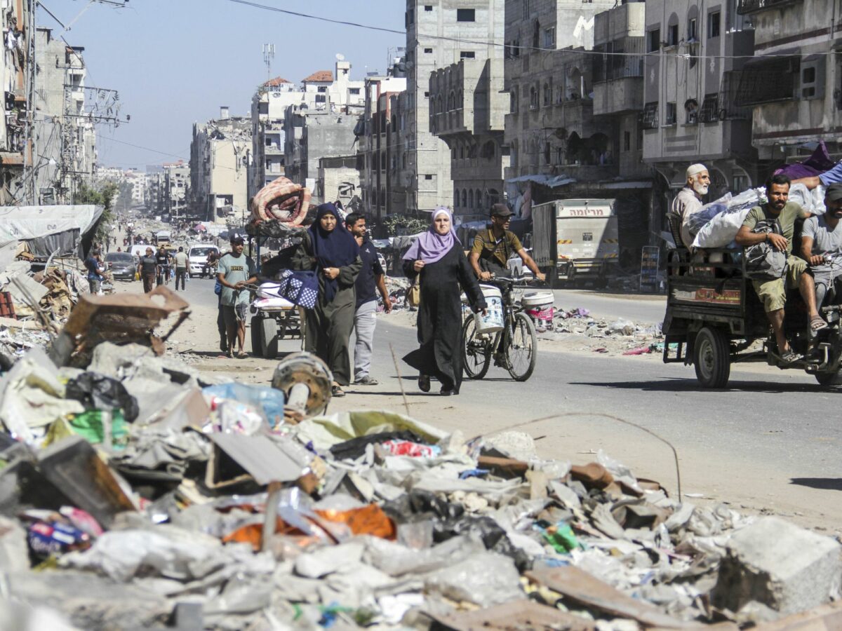 Photo of Palestinians walking among the rubble while fleeing Northern Gaza.