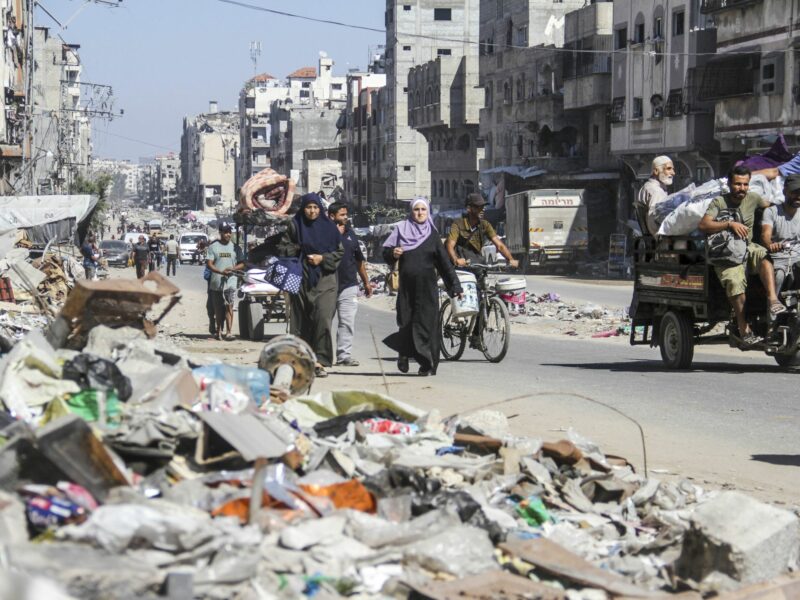 Photo of Palestinians walking among the rubble while fleeing Northern Gaza.