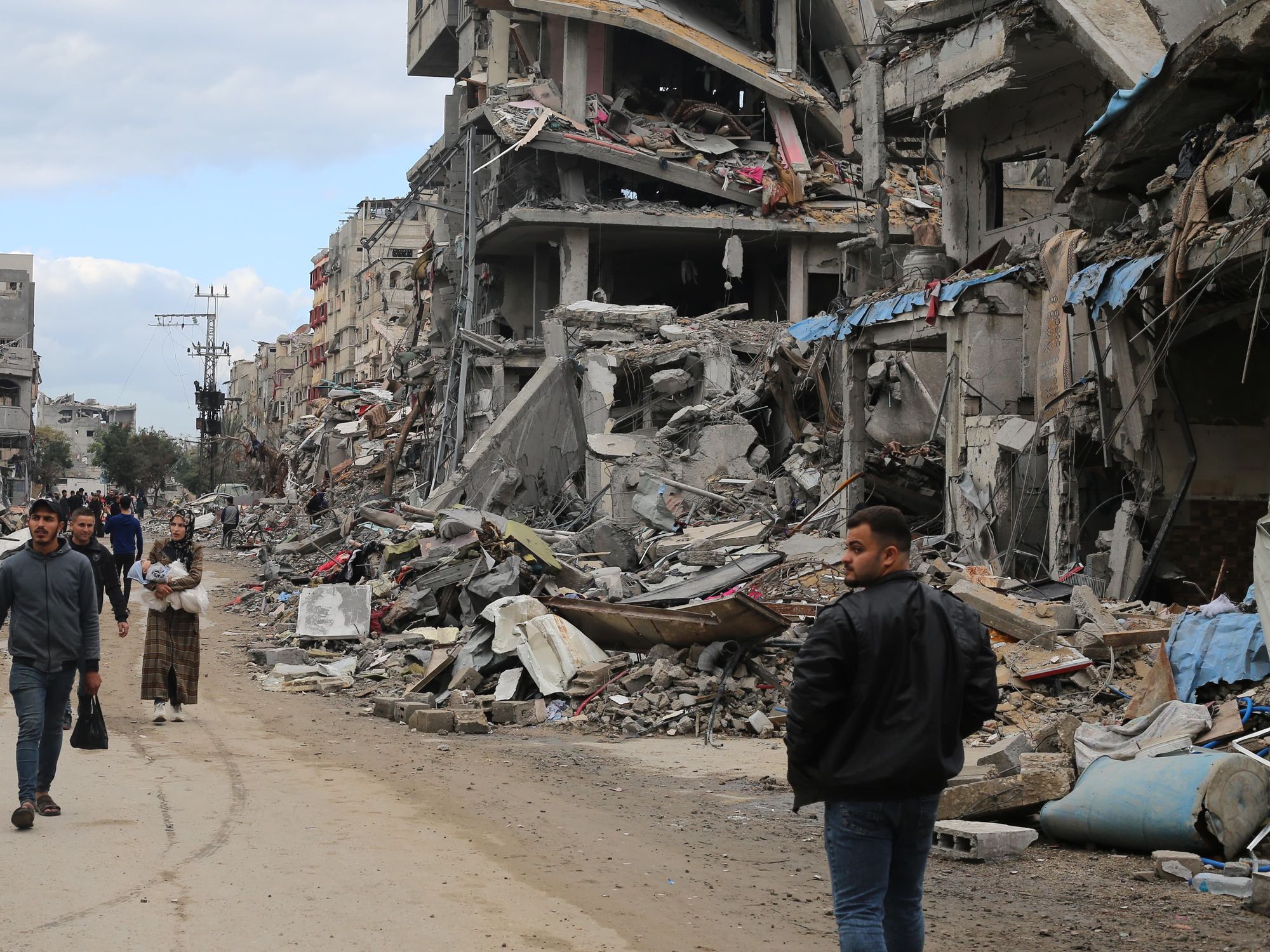 Photo of Palestinians walking in Gaza among the damaged buildings