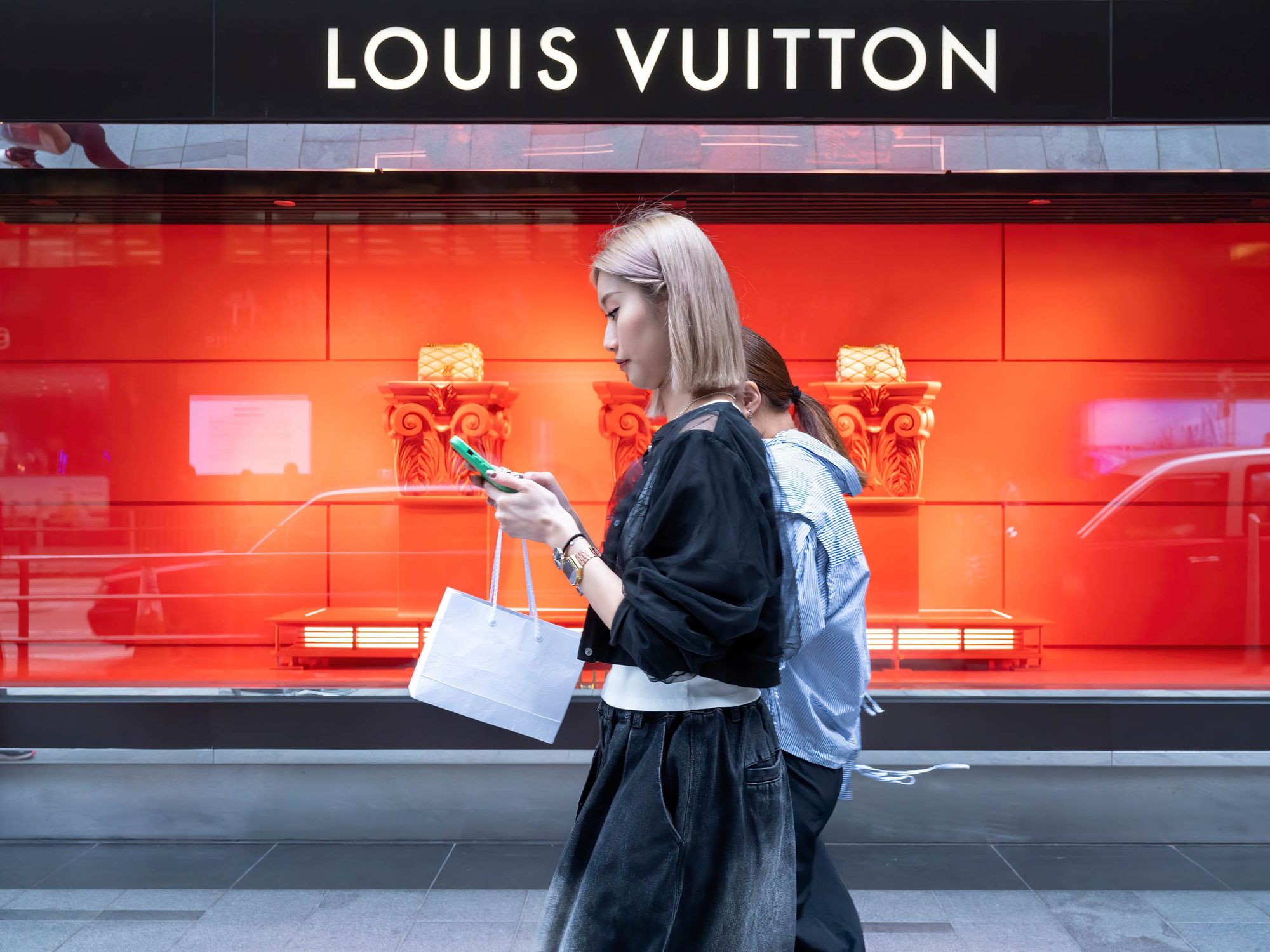 Photo of Pedestrians walk past the French luxury fashion brand Louis Vuitton (LV) store in Hong Kong.