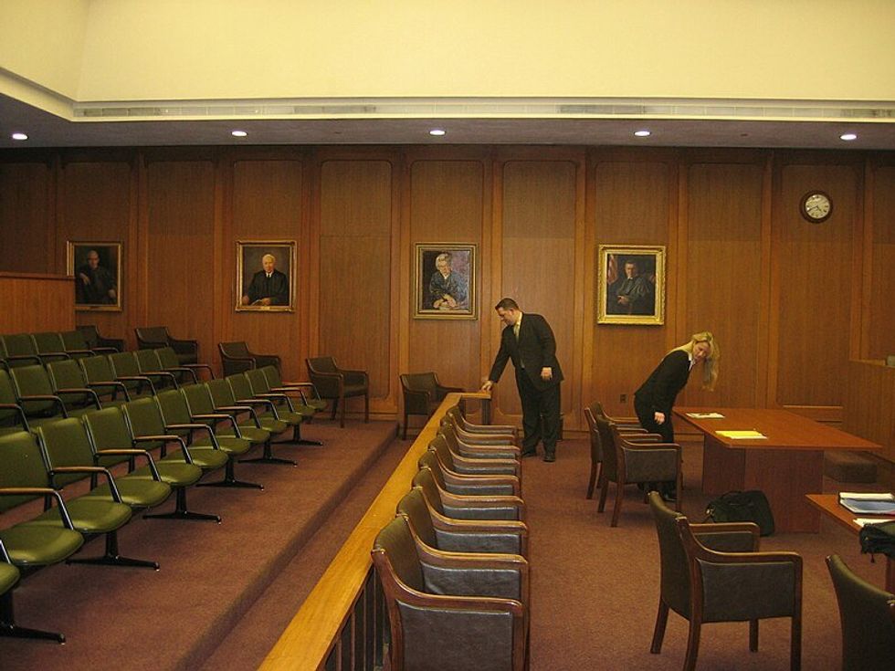 Photo of people adjusting seats in a courtroom