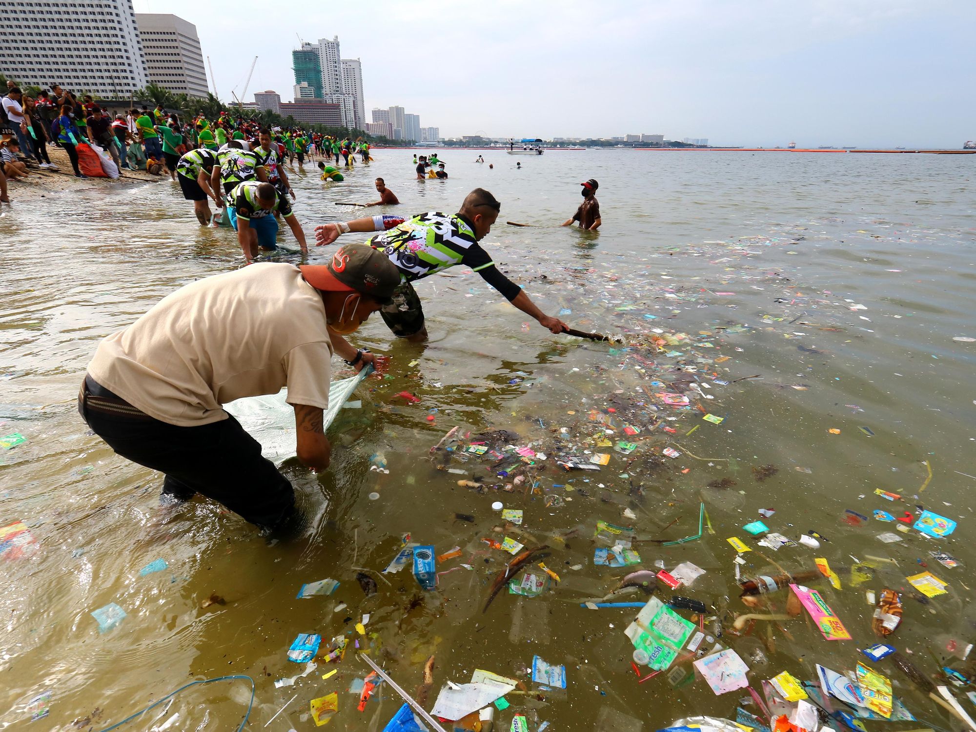photo of people collecting trash from the sea during a mass clean-up mission along the shore of the Manila Bay Dolomites Beach in the Philippines