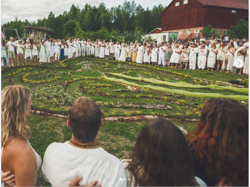 Photo of people dressed in white standing in a circle with arms interlocked
