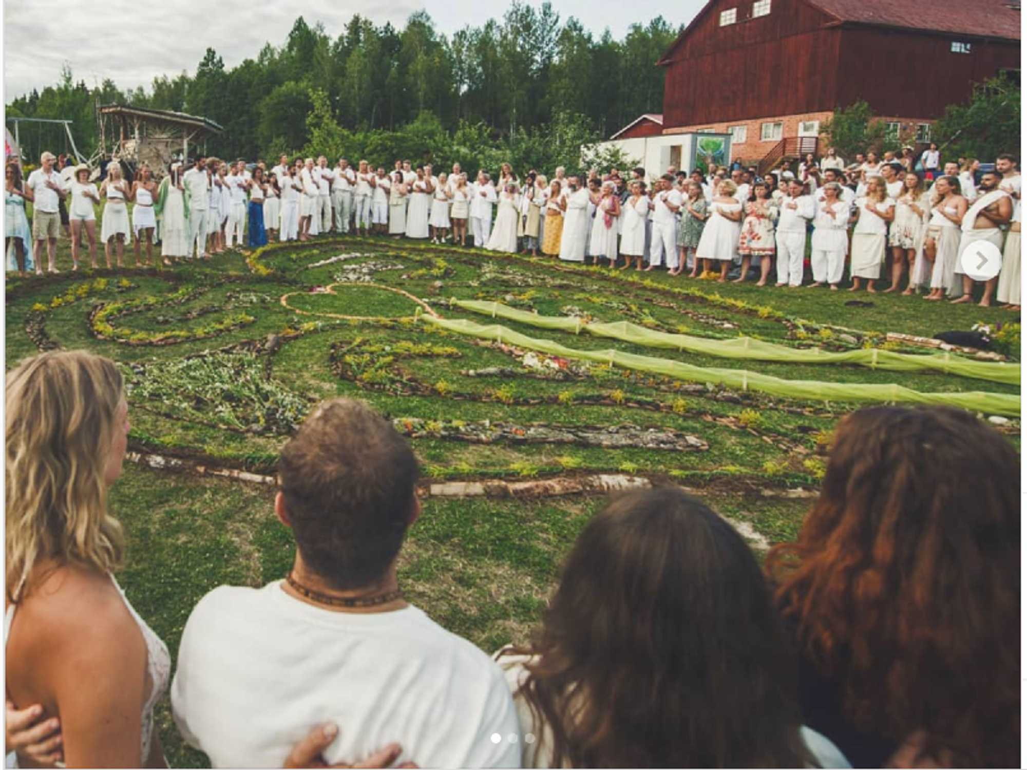 Photo of people dressed in white standing in a circle with arms interlocked