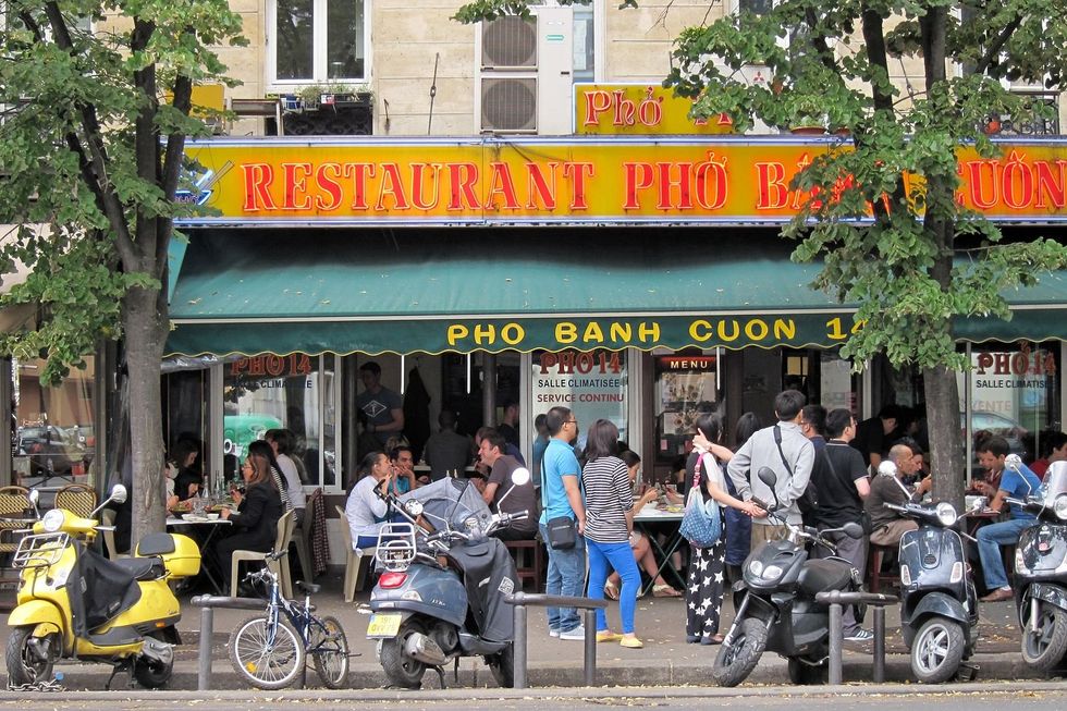 Photo of people eating at ​a Vietnamese restaurant's outside tables in Paris, France