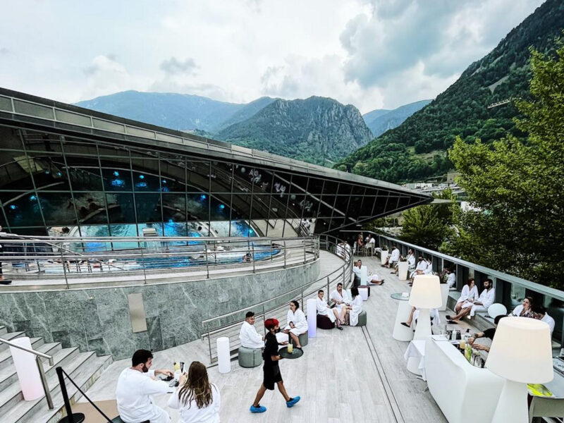 Photo of people enjoying Andorra's Caldea spa, with mountains in the background