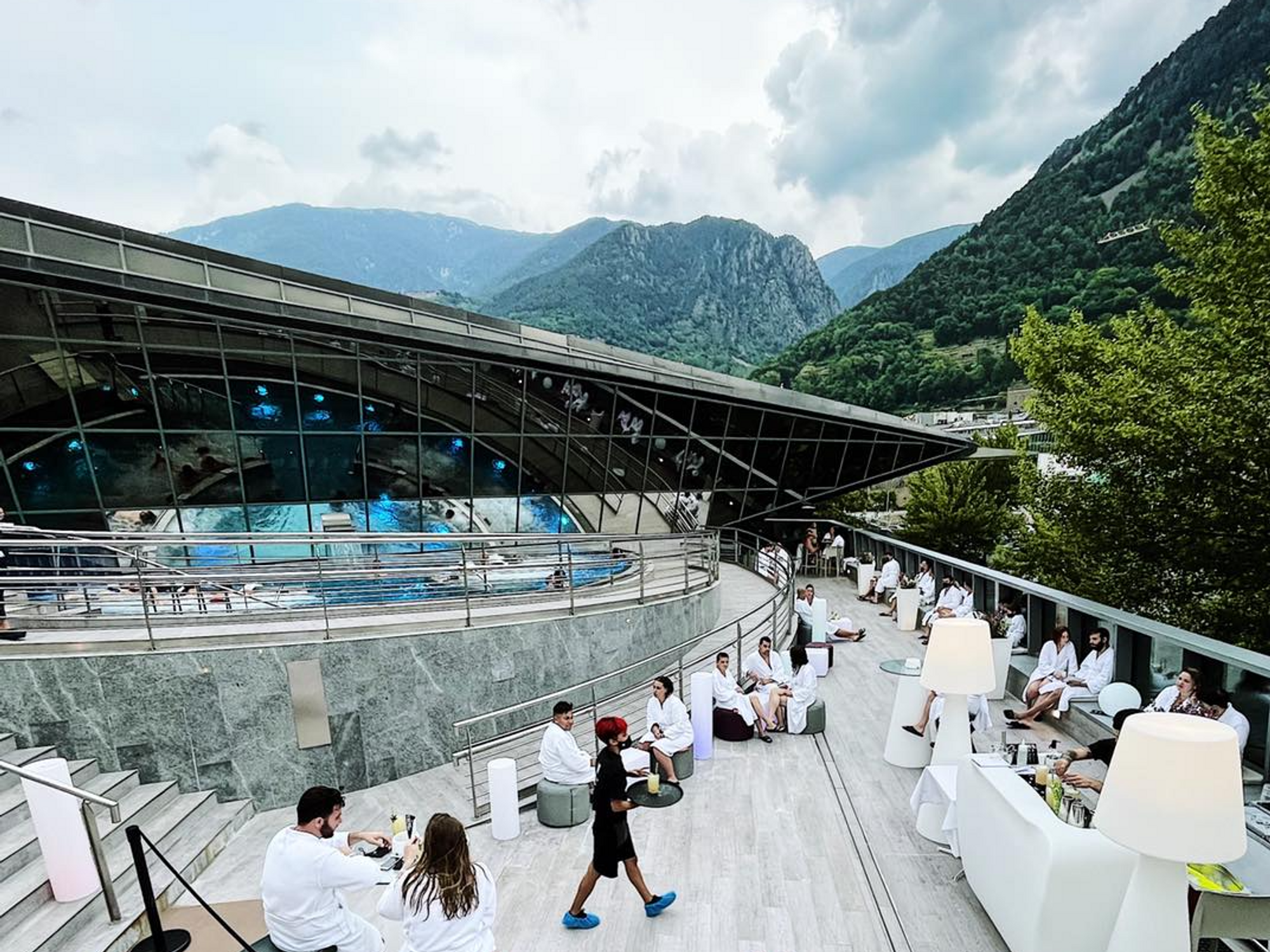 Photo of people enjoying Andorra's Caldea spa, with mountains in the background