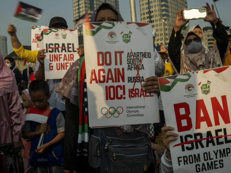photo of people holding signs to ban israel from olympics