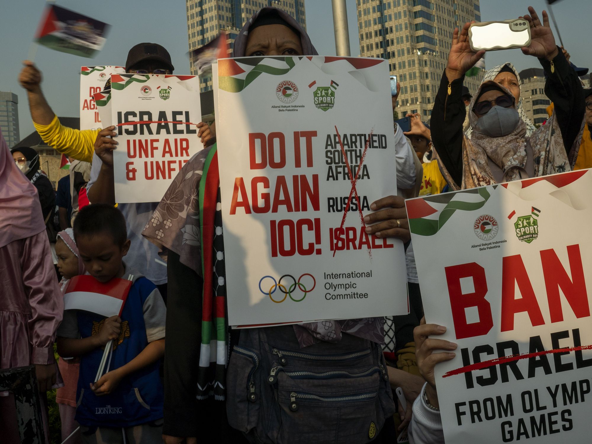photo of people holding signs to ban israel from olympics