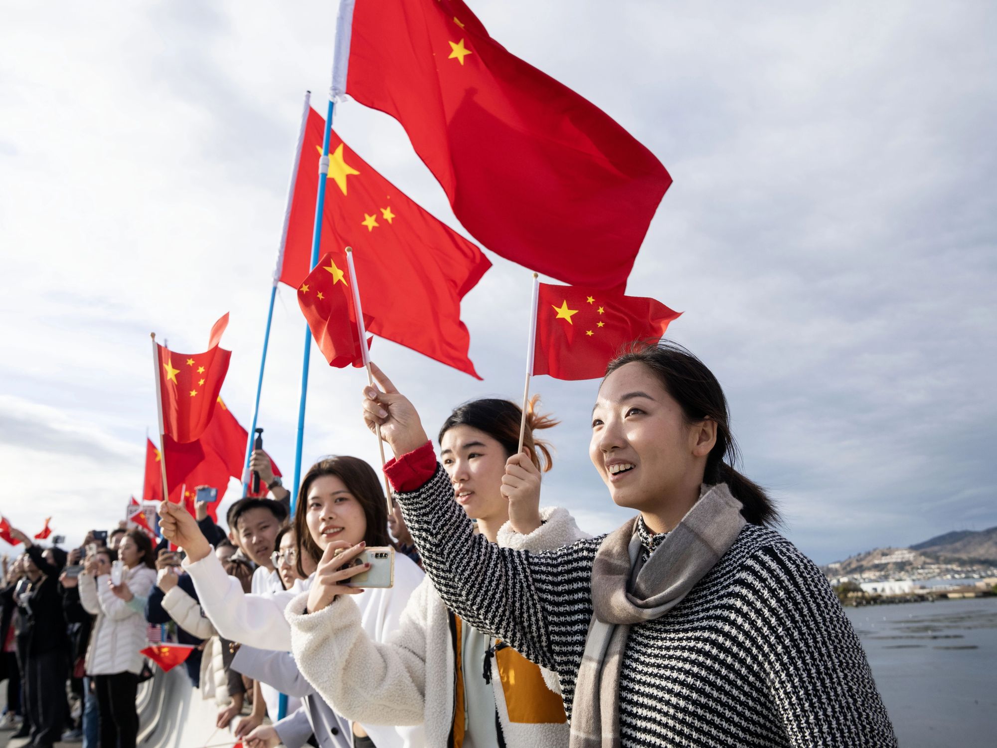 Photo of people in San Francisco welcoming Chinese President Xi Jinping while waving the flag of China