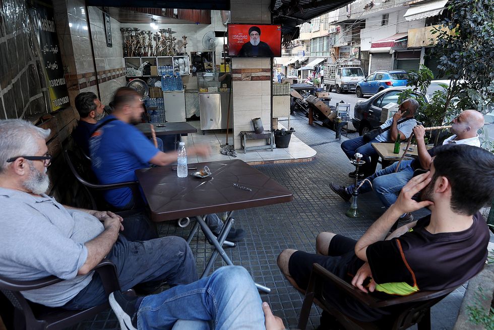 Photo of people listening to a speech by Hezbollah leader Hassan Nasrallah on screen in Beirut, Lebanon.