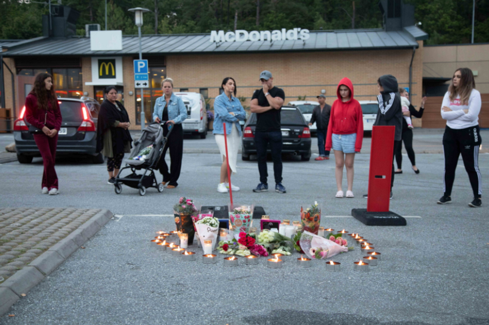 Photo of people looking at candles and flowers at a vigil in memory memorial of victims of a gang shootout in Norsborg, Sweden, in August 2020